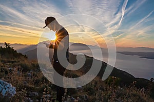 Hiker man with scenic sunrise view from top of mount Kula near Omis, Dinara mountains, Split-Dalmatia, Croatia. Coastal landscape