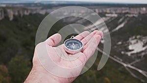 Hiker man searching direction with a compass in mountain valley.