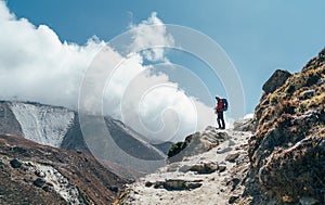 Hiker man silhouette on clouds background standing on path going over the Imja Khola valley and enjoying mountain views during an photo