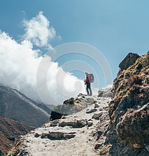 Hiker man silhouette on clouds background standing on path going over the Imja Khola valley and enjoying mountain views during an photo