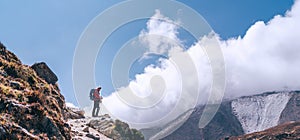 Hiker man silhouette on clouds background standing on path going over the Imja Khola valley and enjoying mountain views during an photo