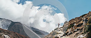 Hiker man silhouette on clouds background standing on path going over the Imja Khola valley during an Everest Base Camp trekking photo