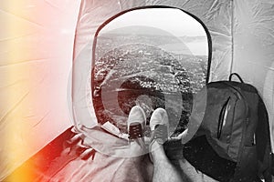 Hiker Man Sitting In A Tourist Tent by City View Vacation Concept. View Of Legs. Point Of View Shot With Scratches