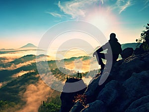 Hiker man take a rest on mountain peak. Man lay on summit, bellow autumn valley.