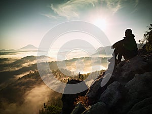 Hiker man take a rest on mountain peak. Man lay on summit, bellow autumn valley.