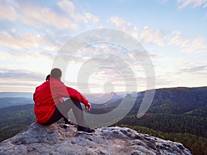 Hiker man take a rest on mountain peak. Man lay on summit, bellow autumn valley