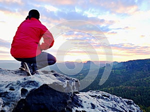 Hiker man take a rest on mountain peak. Man lay on summit, bellow autumn valley. Bright morning Sun