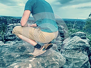 Hiker man take rest on peak. Male legs on sharp summit