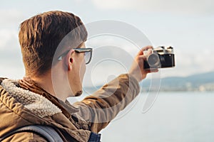Hiker man takes photographs self portrait on coastline