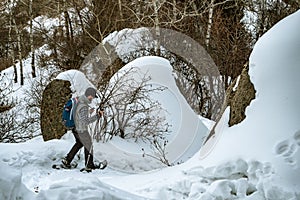 Hiker in the mountains walks on snowshoes. A man alone in the forest descends from the mountain. Winter mountain tourism