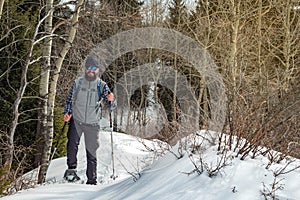 Hiker in the mountains walks on snowshoes. The man is alone in the forest. Winter mountain tourism