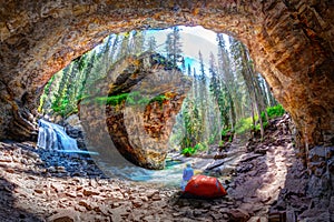 Hiker outside his camping tent at Hidden Cave with waterfall and limestone bedrock in Johnston Canyon at Banff National Park photo