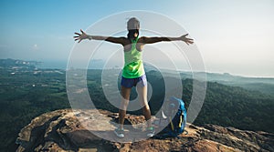 hiker outstretched arms on mountain top cliff edge