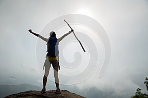 Hiker outstretched arms on sunrise mountain peak cliff edge