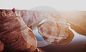 Hiker overlooking Horseshoe Bend at sunset, Arizona, USA