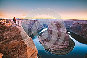 Hiker overlooking Horseshoe Bend at sunset, Arizona, USA