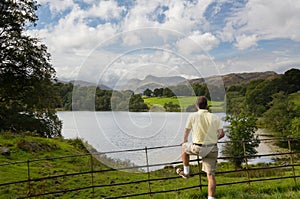 Hiker overlooks Loughrigg Tarn in Lake District