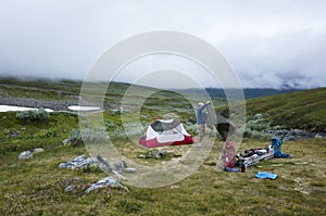 Hiker packing tent, Hiking in Swedish Lapland on Kungsleden trail in northern Sweden. Arctic mountain nature of Scandinavia