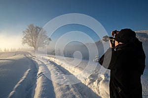 Hiker photographer taking pictures of snowy nature in winter mountains