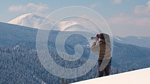 Hiker photographer taking pictures of snowy nature in winter mountains.