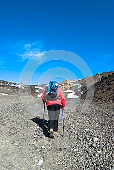 Hiker with poles walking the stony trail photo