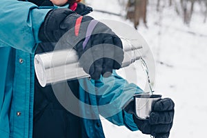 Hiker pours tea from the thermos in the winter