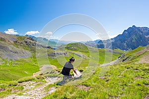 Hiker reading trekking map while resting at panoramic mountain spot. Outdoors activities, summer adventures and exploration on the
