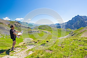 Hiker reading trekking map while resting at panoramic mountain spot. Outdoors activities, summer adventures and exploration on the