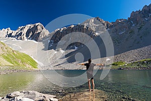 Hiker relaxing at high altitude blue lake in idyllic uncontaminated environment once covered by glaciers. Summer adventures and ex