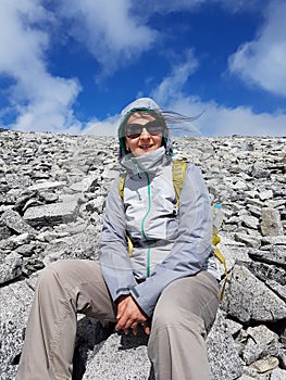 Hiker resting in the middle of the rocky mountain slope