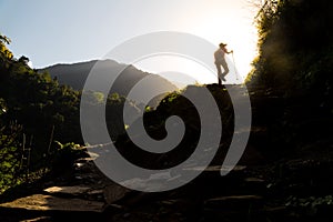 Hiker in silhouette hiking at highland towards sunrise. Lens flare intended