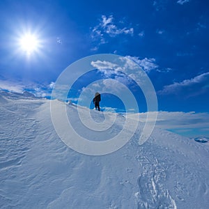 hiker silhouette on snowbound mount slope under a sparkle sun