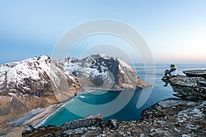 Hiker sits on the top of the mountain Ryten in Lofoten islands in Norway