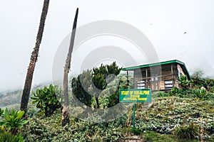 A hiker sitting next to a cabin at Mount Muhabura in the Mgahinga Gorilla National Park, Uganda