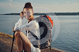 Hiker smiling happily while sitting near lakeside