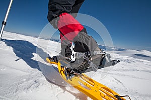 Hiker snowshoeing in winter mountains during sunny day