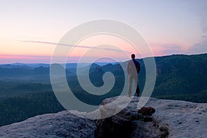 Hiker stand on the cliff of sandstone rock empire and watch over the misty and foggy morning valley