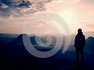 Hiker stand on the sharp corner of sandstone rock in rock empires park and watching over the misty and foggy morning valley to Sun