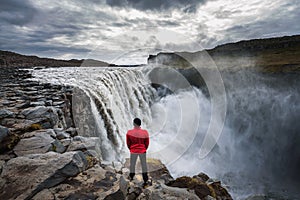 Hiker standing close to the Dettifoss waterfall in Iceland