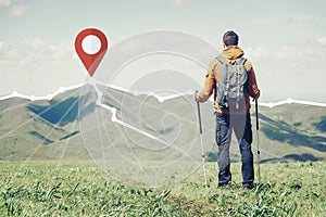 Hiker standing in front of GPS pin on peak of mountain.