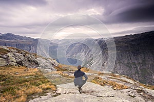 Hiker is standing on a mountain top and watching over a calm lake, Beautiful moment miracle of nature. Hiker silhouette