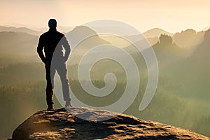 Hiker is standing on the peak of sandstone rock in rock empires park and watching over the misty and foggy morning valley to Sun.