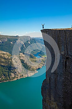 Hiker standing on Preikestolen and looking on the fjerd, Preikestolen - famous cliff at the Norwegian mountains