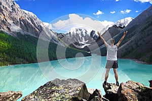 Hiker standing with raised hands near the beautiful mountain lake and enjoying valley view