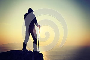 hiker standing on sunrise seaside cliff edge