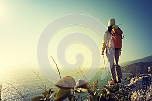 Hiker standing on sunrise seaside cliff edge