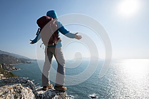 Hiker standing on sunrise seaside mountain cliff edge