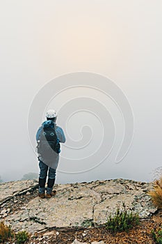 hiker standing on top of a cliff on a hill looking at the horizon . With copy space photo