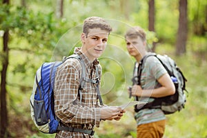 Hiker standing in the woods with a friend and looking at the cam