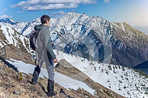 Hiker stands on top and looks up at the sky and snowy mountains around. Concept of travel and achieve the goal